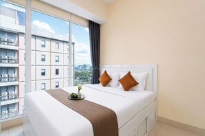 A hotel room with a large bed, a view of the city, and a balcony with air conditioning units. - Comfortable And Homey 1Br At Apartment Tree Park City Bsd (Tangerang)