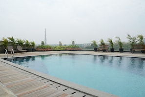 A rooftop swimming pool with wooden deck, benches, and potted plants. - Comfortable And Homey 1Br At Apartment Tree Park City Bsd (Tangerang)