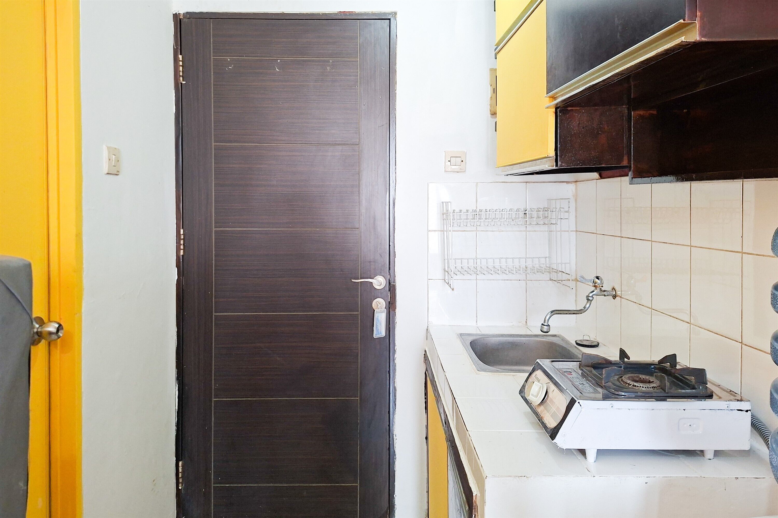 A compact kitchen with a dark wooden door, a white sink, and a gas stove.