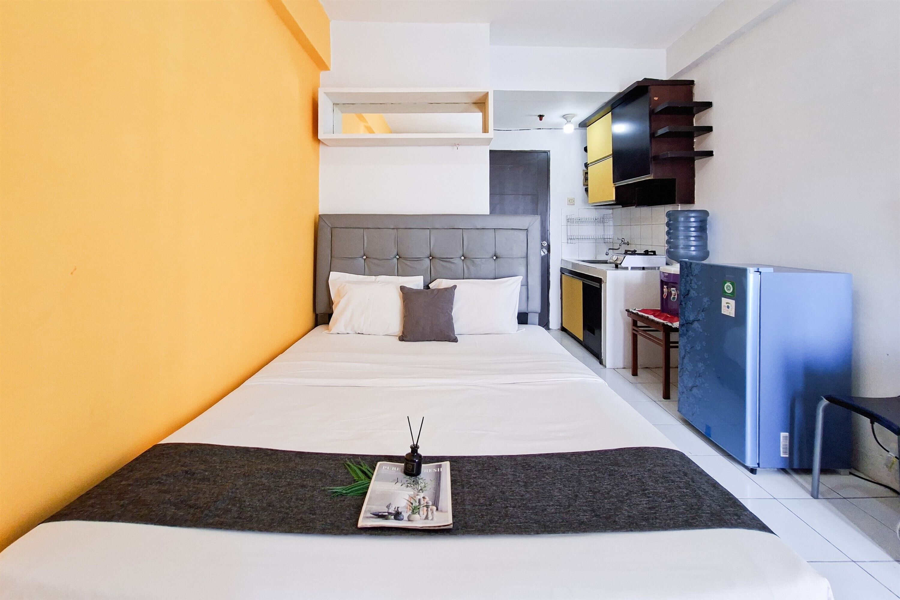 A hotel room with a bed, a small kitchenette, and a water dispenser.
