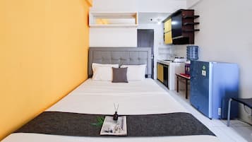 A hotel room with a bed, a small kitchenette, and a water dispenser.