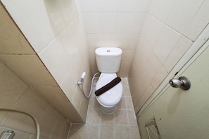 Ein kleines, schmales Badezimmer mit Toilette, einem Händetrockner und einer Tür mit rundem Griff.