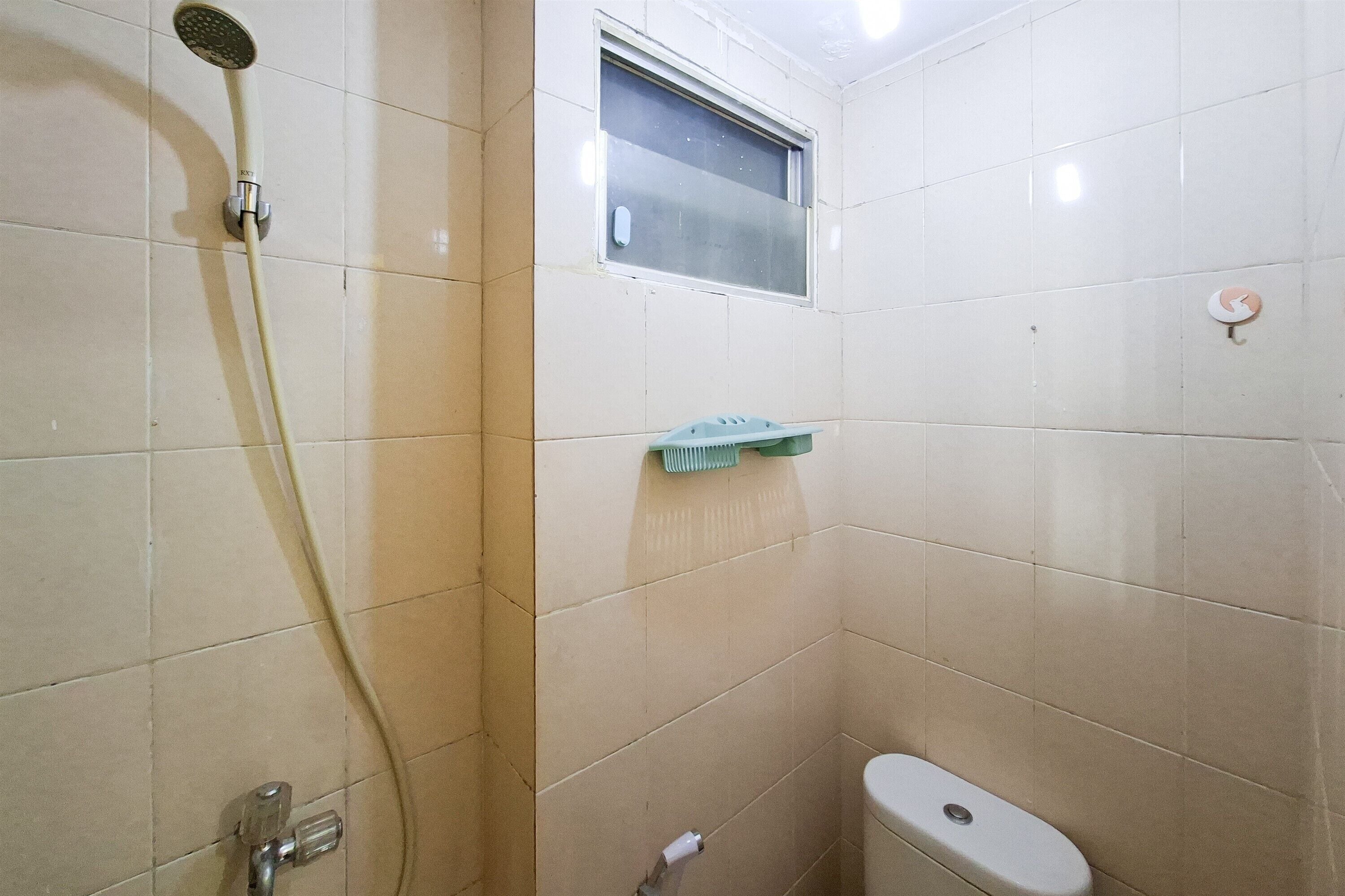 Un baño pequeño con ducha, inodoro y ventana.