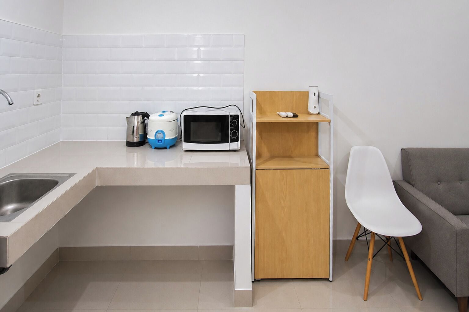 Une cuisine compacte équipée d’un four à micro-ondes, d’une bouilloire et d’un petit meuble en bois.