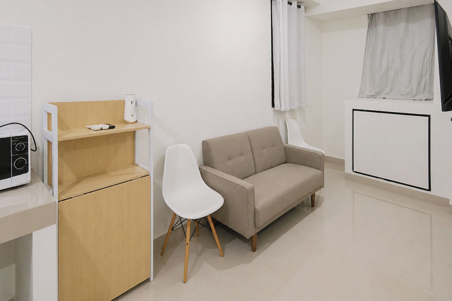A modern, minimalistic room with a wooden cabinet, a white chair, a beige sofa, and a white radiator.