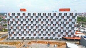 Edifici modern amb un disseny de finestres repetitiu, una zona d'aparcament i un cel serè.