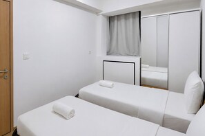 A hotel room with two single beds, a wooden door, a mirror, and a window with a curtain. - Serene Modern 1Br (No Kitchen) At Apartment Bandaraya - Tallasa City Makassar (Makassar (Ujung Pandang))