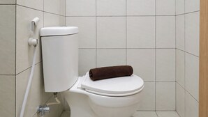 Lavabo blanc amb una tovallola marró a l'assent, una palanca de descàrrega blanca i una canonada visible.