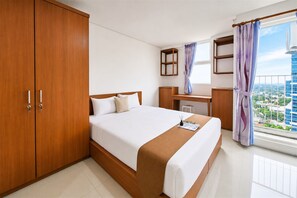 Ein Hotelzimmer mit Bett, Schreibtisch, Kleiderschrank und Blick auf die Stadt.