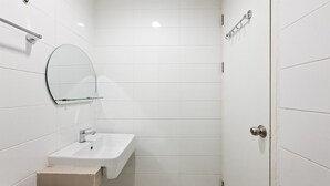 A bathroom with a white sink, a mirror, and a door. - Bright And Comfortable Studio Room At Apartment Tuscany Residence (South Tangerang)