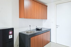 A small kitchen with a sink, a countertop, and wooden cabinets. - Bright And Comfortable Studio Room At Apartment Tuscany Residence (South Tangerang)