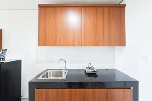 Eine Küche mit schwarzer Arbeitsplatte, Spüle aus Edelstahl und Holzschränken.