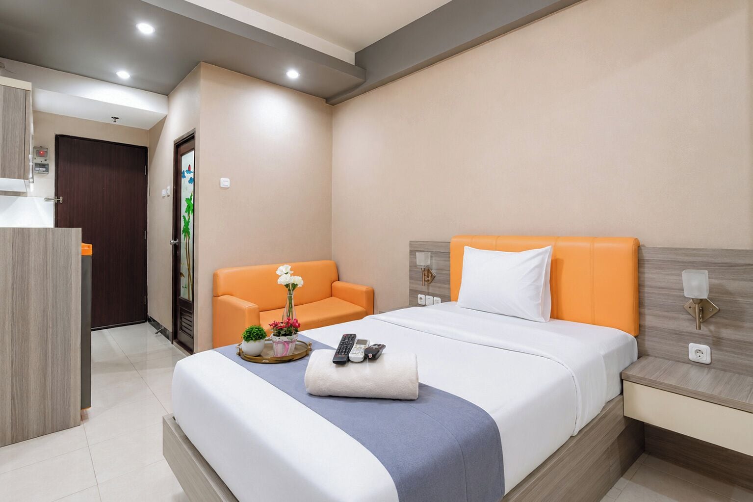 Ein Hotelzimmer mit einem Bett, einem Nachttisch, einem Sessel und einem kleinen Tisch mit Blumen.