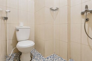 A bathroom with a toilet, a shower, and a tiled floor.