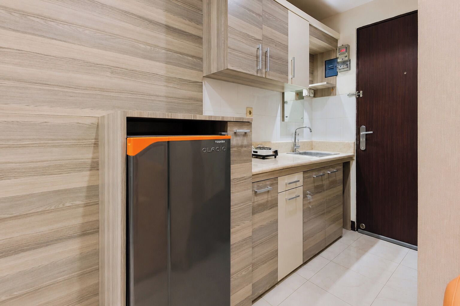 A kitchen with a refrigerator, dishwasher, and a wooden cabinet.