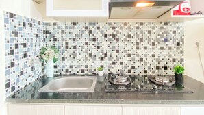 Una cocina con salpicadero de azulejos, un lavamanos de acero inoxidable y una estufa a gas.