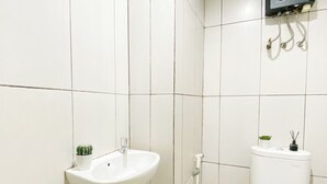A bathroom with a white sink, a toilet, and a shower. - Minimalist Functional Studio At Apartment Grand Kamala Lagoon (Bekasi)