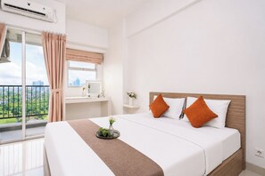 Ein Hotelzimmer mit Bett, Schreibtisch, Fenster mit Vorhängen und Blick auf die Stadt.