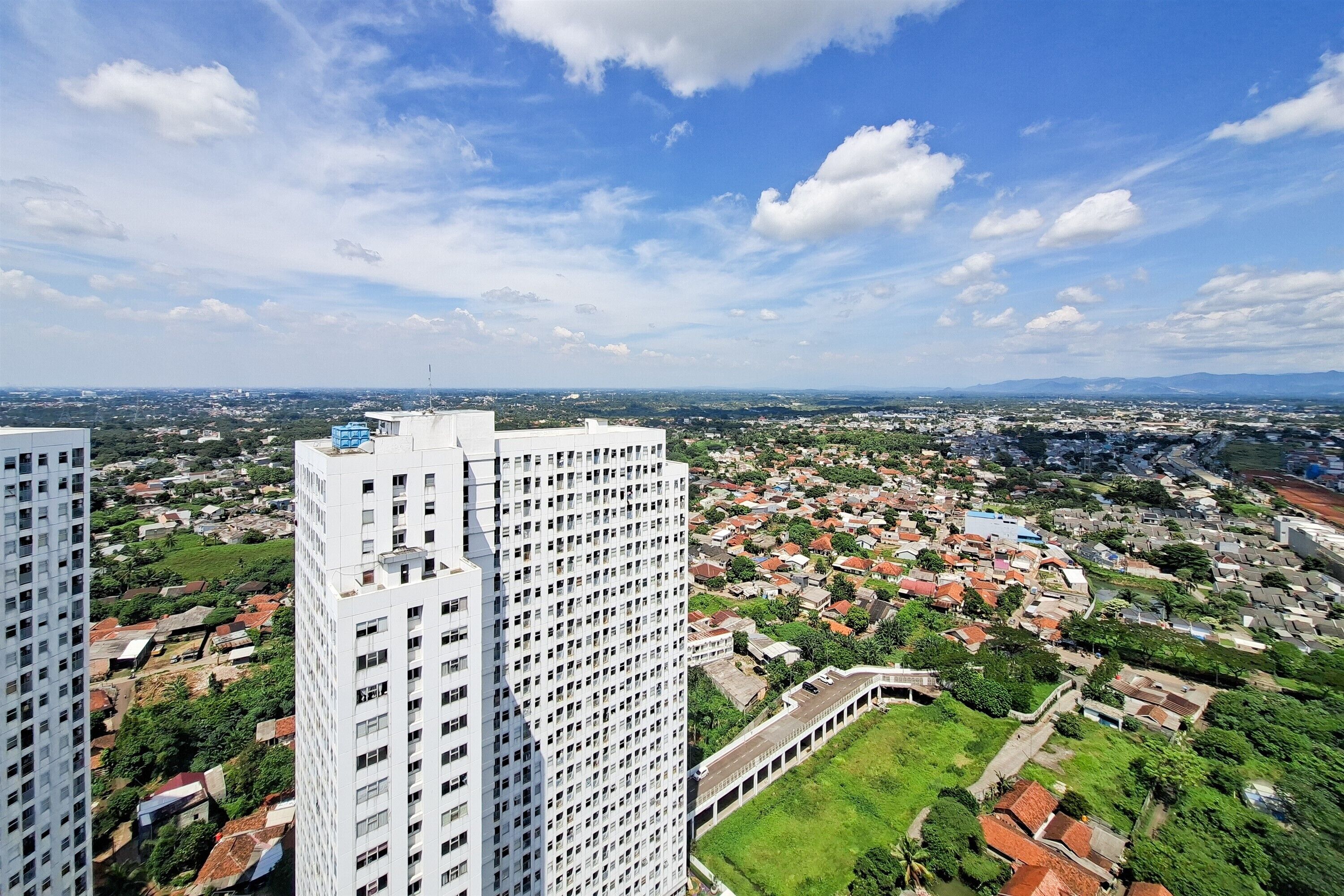 Um edifício alto com vista para uma área urbana densamente povoada, com diversos edifícios e áreas verdes.