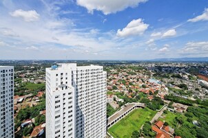 Um edifício alto com vista para uma área urbana densamente povoada, com diversos edifícios e áreas verdes.