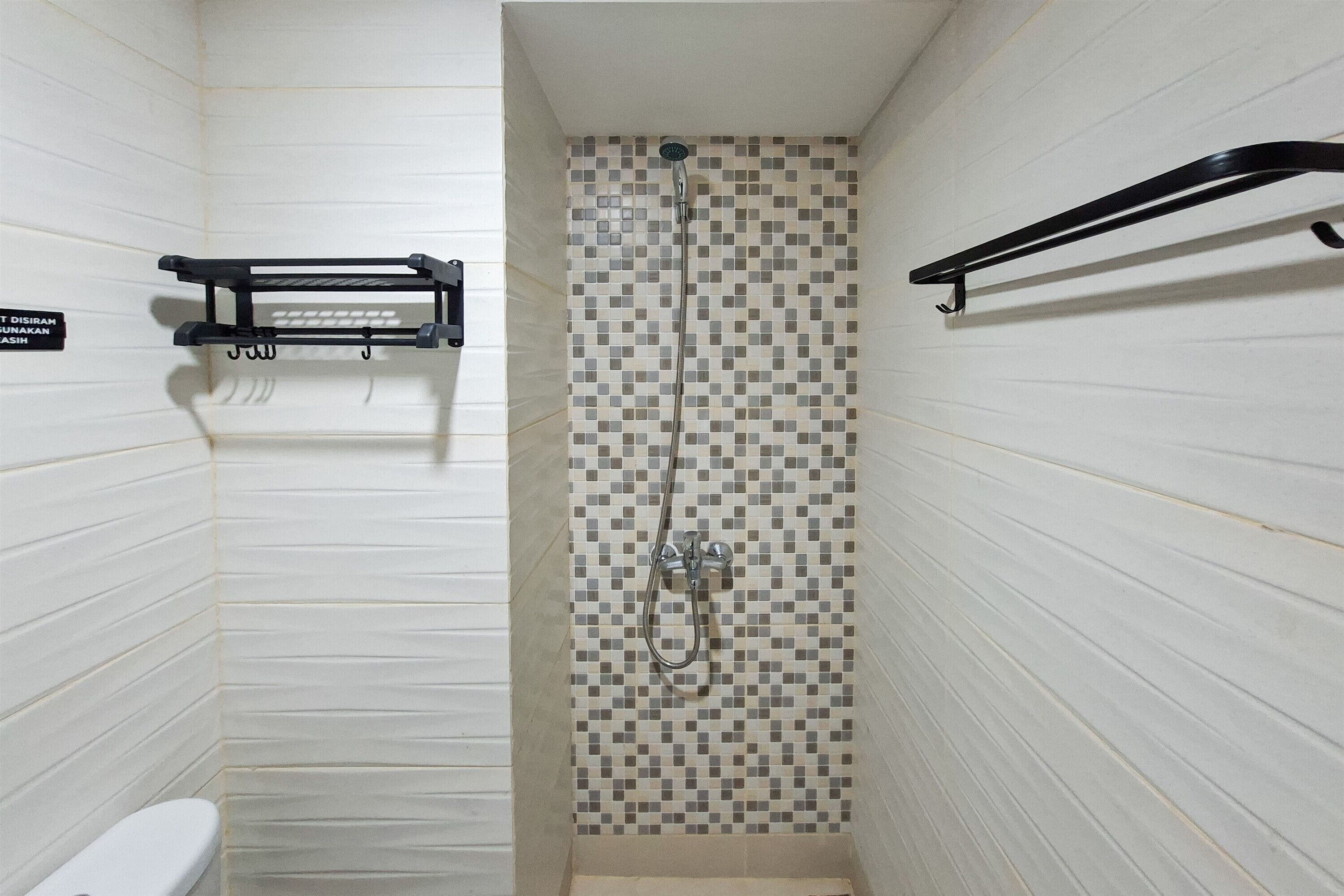A small, tiled shower area with a showerhead and a handheld shower attachment.
