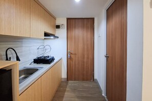 Eine kompakte Küche mit Holzausbau, einer Edelstahl-Spüle und einer kleinen Arbeitsfläche.