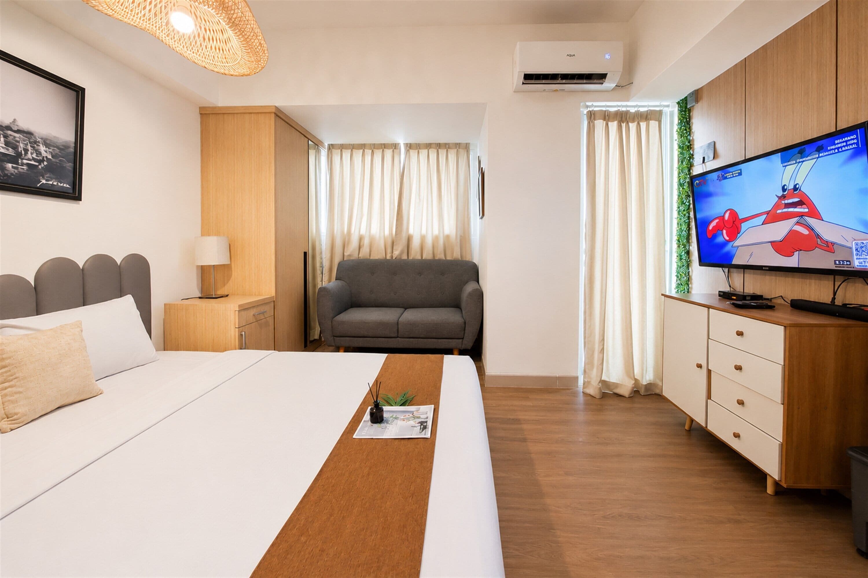 Une chambre d’hôtel avec un lit, un bureau, une chaise, une télévision et des rideaux.