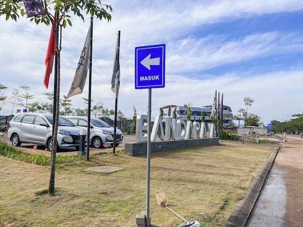 Un área de estacionamiento con coches y un letrero azul que indica 'MASUK' (entrar).