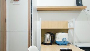 A kitchenette with a kettle, a rice cooker, and a remote control on a table. - Comfortable Studio (No Kitchen) At Apartment Bandaraya - Tallasa City Makassar (Makassar (Ujung Pandang))