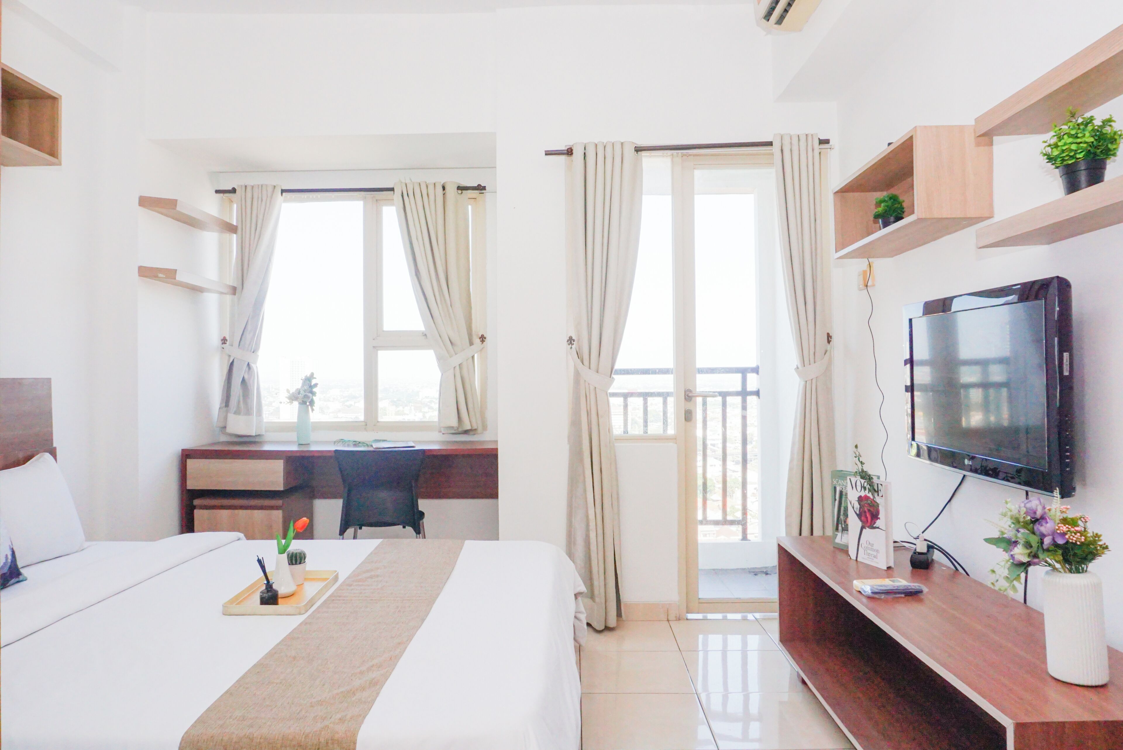A hotel room with a bed, a desk, a television, and a balcony.