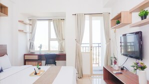 Een hotelkamer met een bed, een bureau, een televisie en een balkon.