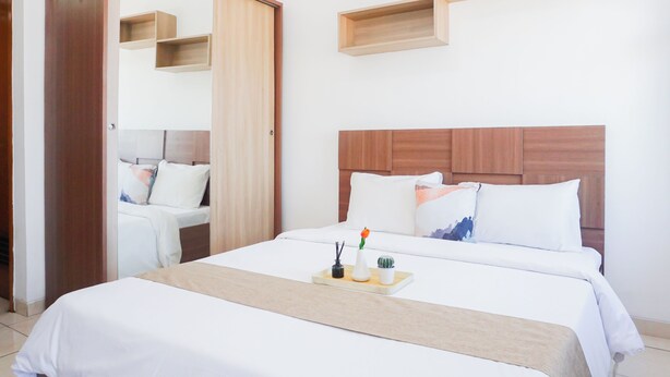 Een hotelkamer met een bed, nachtkastjes, een garderobe en inbouwplanken.