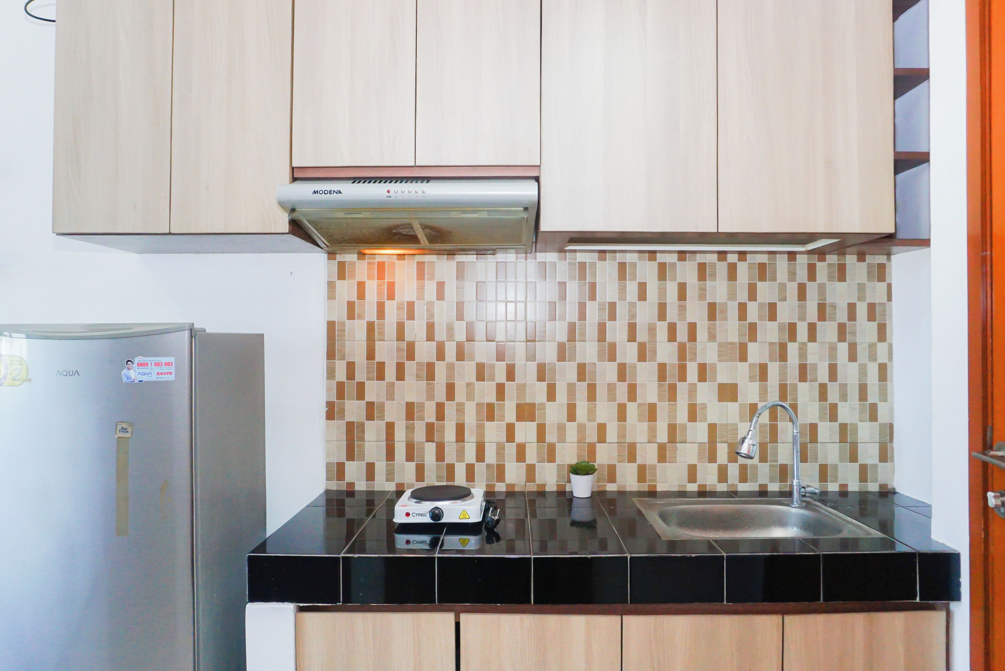 Una cocina con un refrigerador de acero inoxidable, un horno empotrado, un microondas y un lavamanos con un grifo moderno.