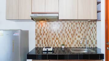 Una cocina con un refrigerador de acero inoxidable, un horno empotrado, un microondas y un lavamanos con un grifo moderno.