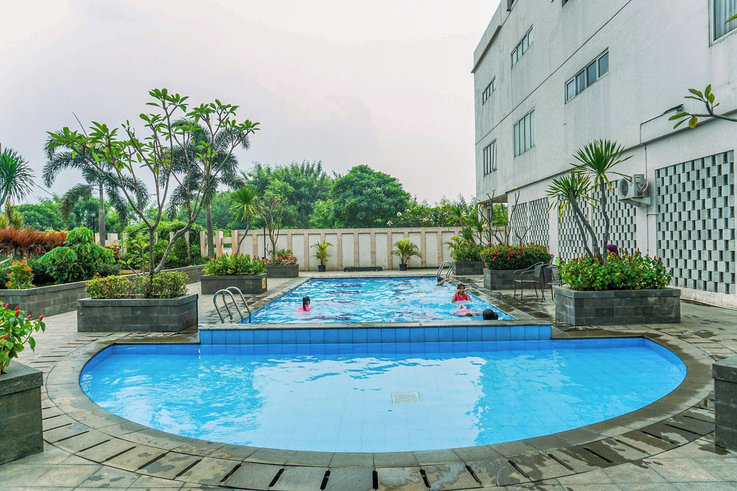 A swimming pool surrounded by planters and a building.