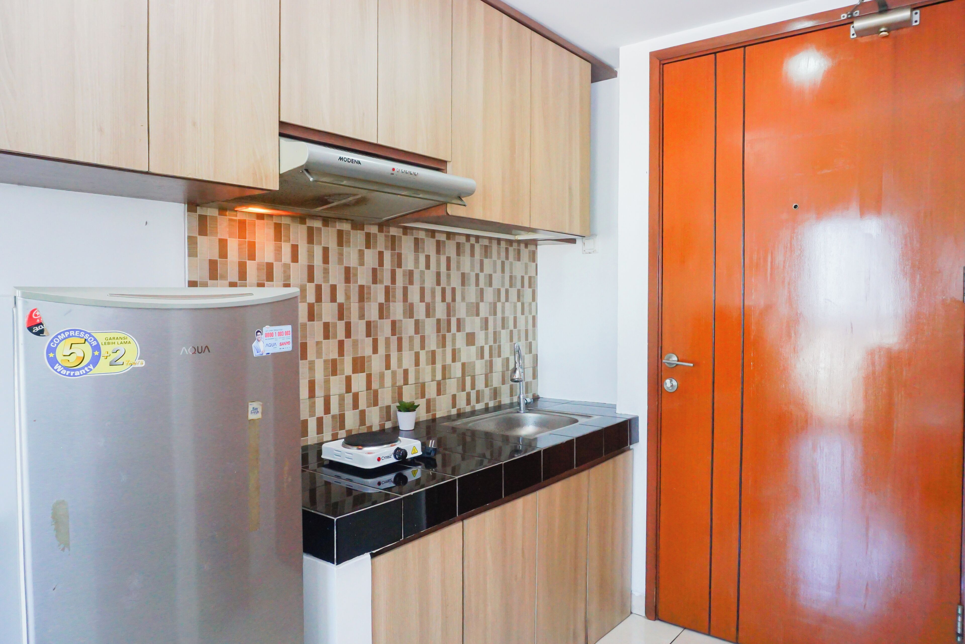 Cozinha compacta com geladeira, fogão e pia.