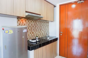 Cocina compacta con refrigerador, estufa y lavamanos.