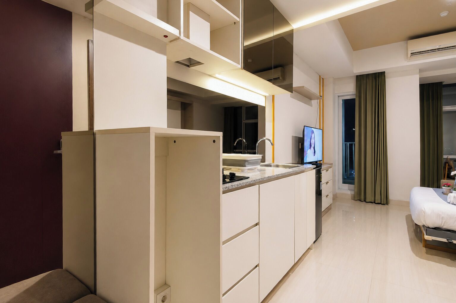 A modern kitchen with a built-in refrigerator, a sink, and a television.