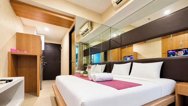 A modern hotel room with a large bed, a desk, and a television. - Comfortable And Practical Living Studio Room At Apartment Tamansari Papilio (Surabaya)