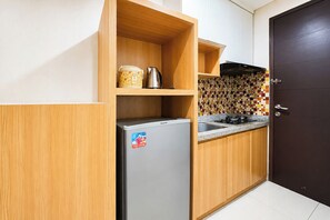 Une cuisine de taille réduite équipée d’un réfrigérateur, d’une machine à café et d’un crédence carrelée.
