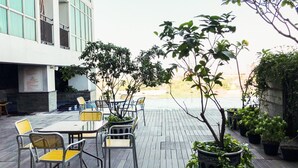 An outdoor seating area with tables and chairs, surrounded by potted plants and a view of a building. - Comfortable And Practical Living Studio Room At Apartment Tamansari Papilio (Surabaya)