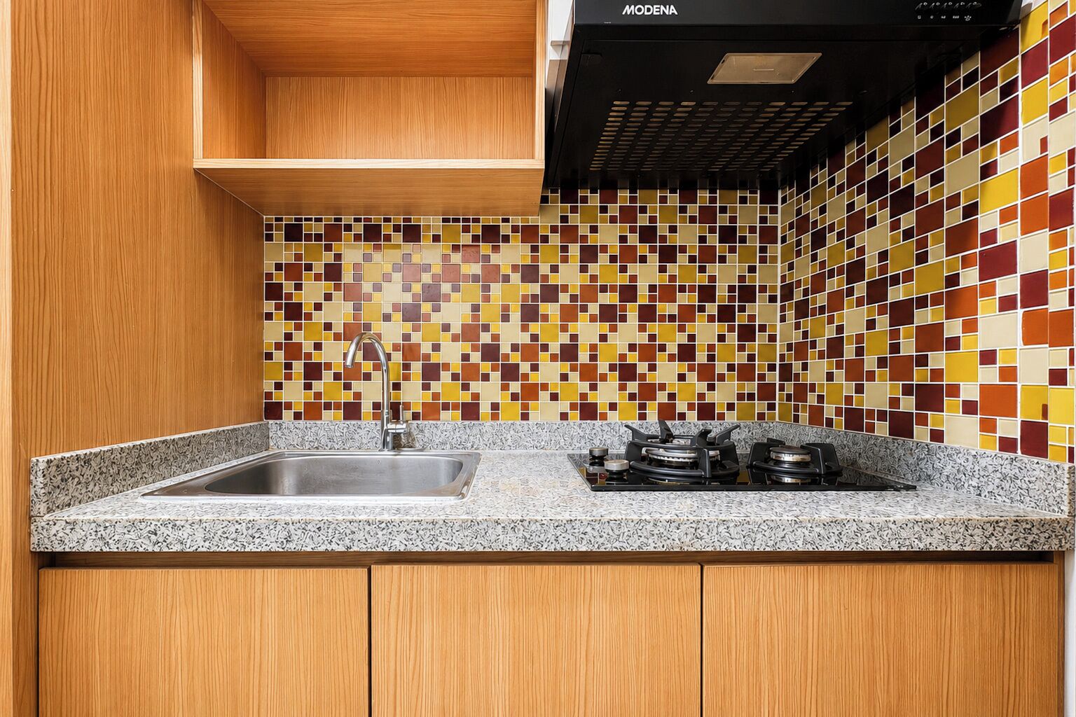 A kitchen with a granite countertop, a stainless steel sink, a gas stove, and a tiled backsplash with a geometric pattern.