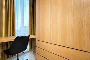 Une pièce avec une armoire en bois, une chaise noire et une fenêtre avec des rideaux.