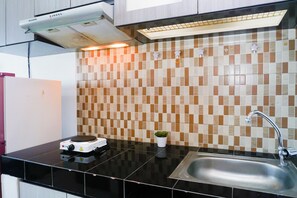 Une cuisine moderne avec un plan de travail noir, un évier en acier inoxydable, une cuisinière blanche et un pare-feu en carreaux.