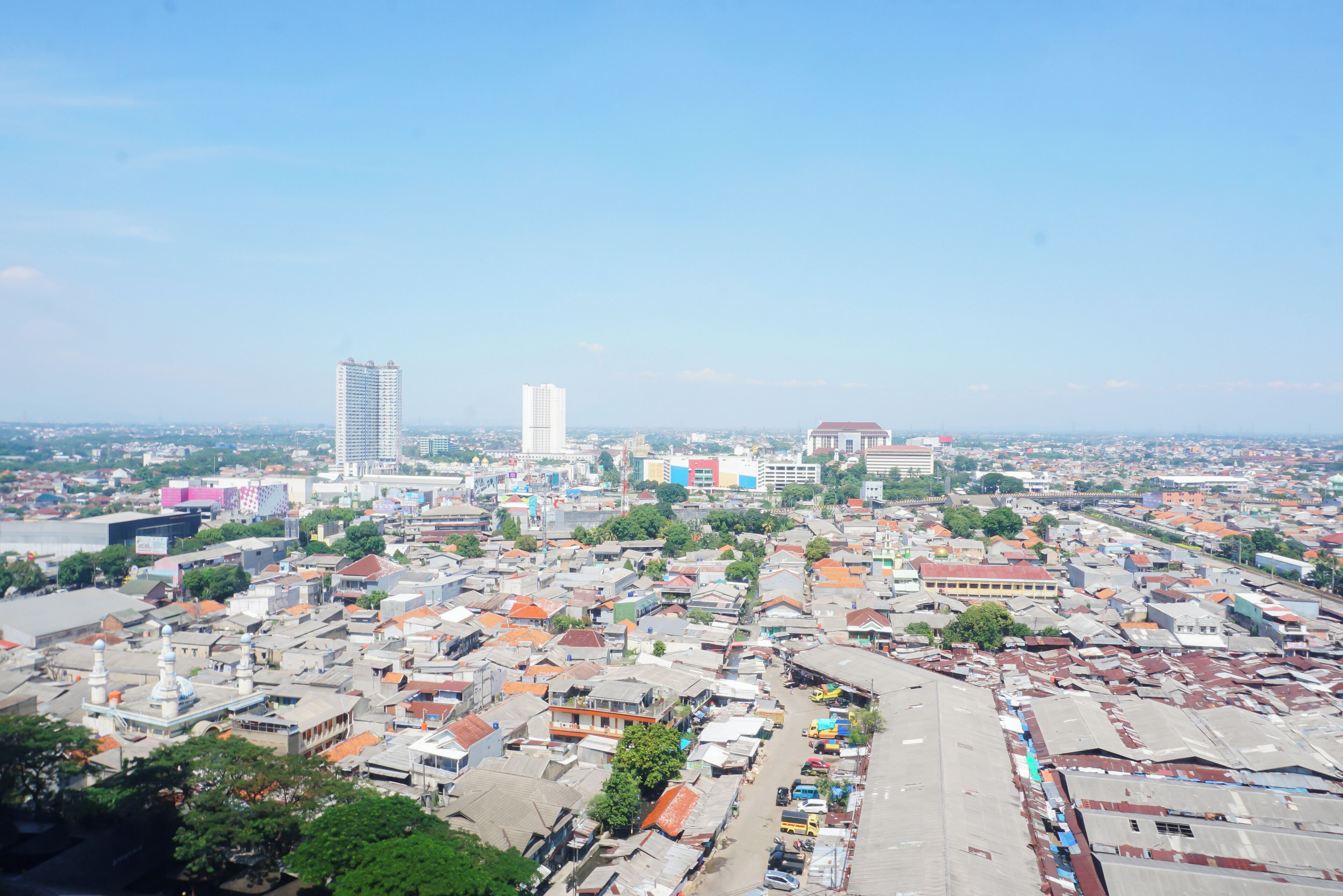A cityscape with dense urban buildings, a prominent tall building, and a mix of residential and commercial structures.