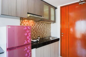 A kitchen with a pink refrigerator, a tiled backsplash, and a wooden cabinet above the stove. - Cozy And Relaxing Studio At Apartment Margonda Residence 5 (Depok)