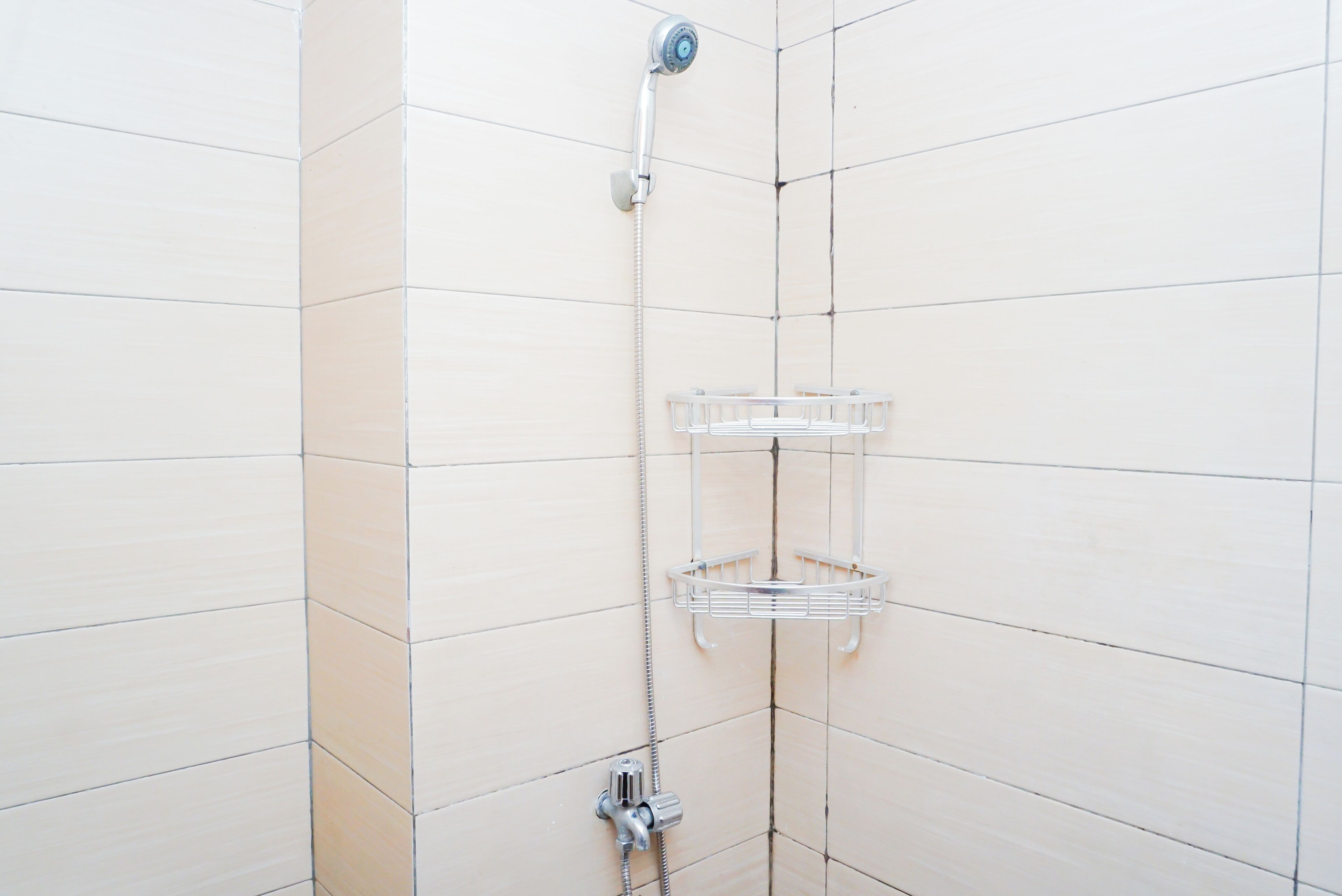 Eine Dusche mit einem chromfarbenen Wasserhahn und einer durchsichtigen Ablage.