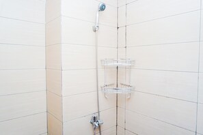 A shower with a chrome faucet and a clear plastic shelf. - Cozy And Relaxing Studio At Apartment Margonda Residence 5 (Depok)