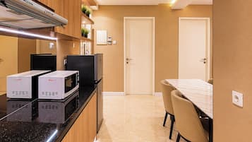 Een compacte keuken met ingebouwde apparatuur, een eethoek met tafel en stoelen, en een deur die naar een andere kamer leidt.