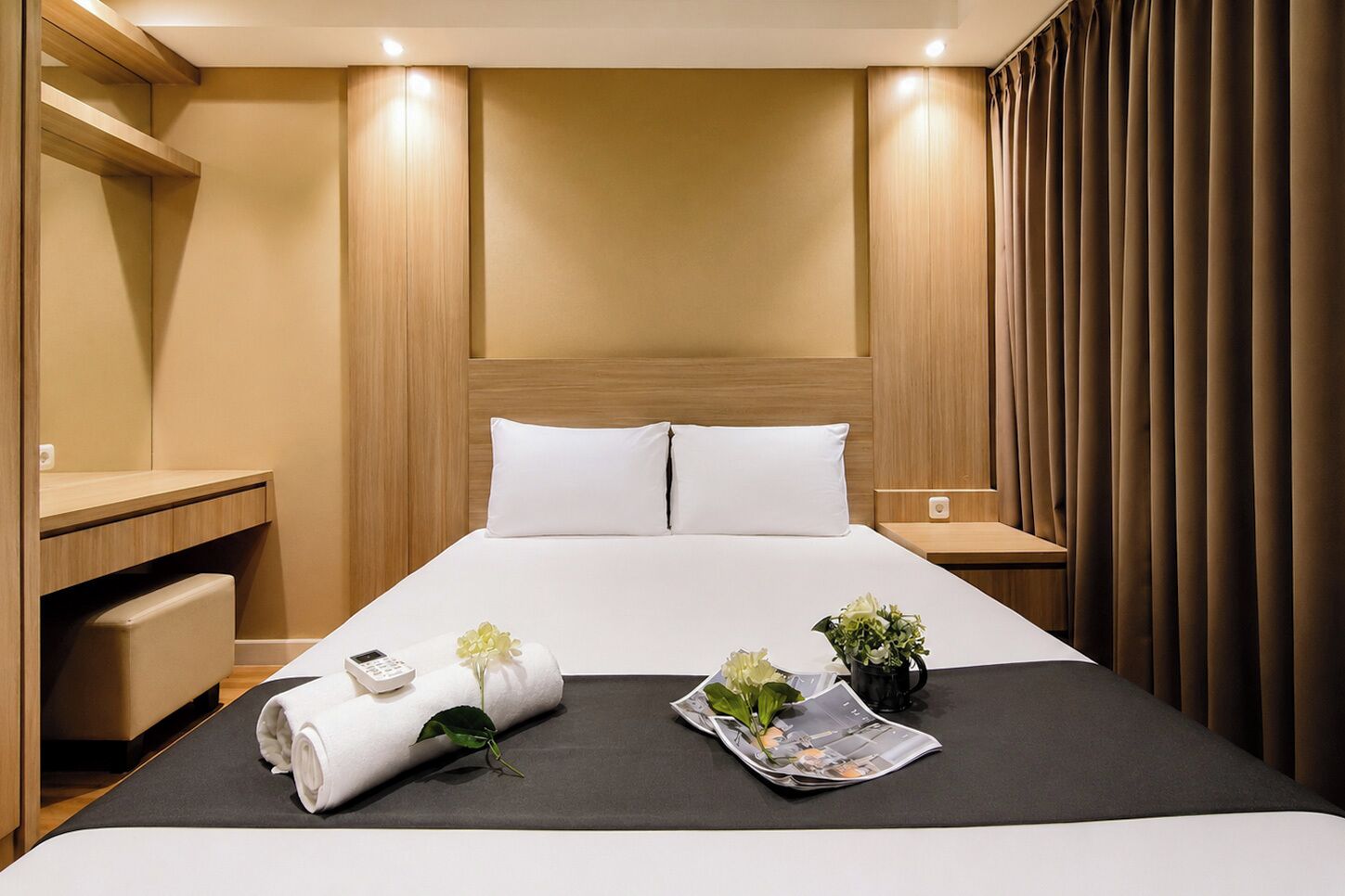 A hotel room with a bed, bedside tables, a mirror, and a curtain.